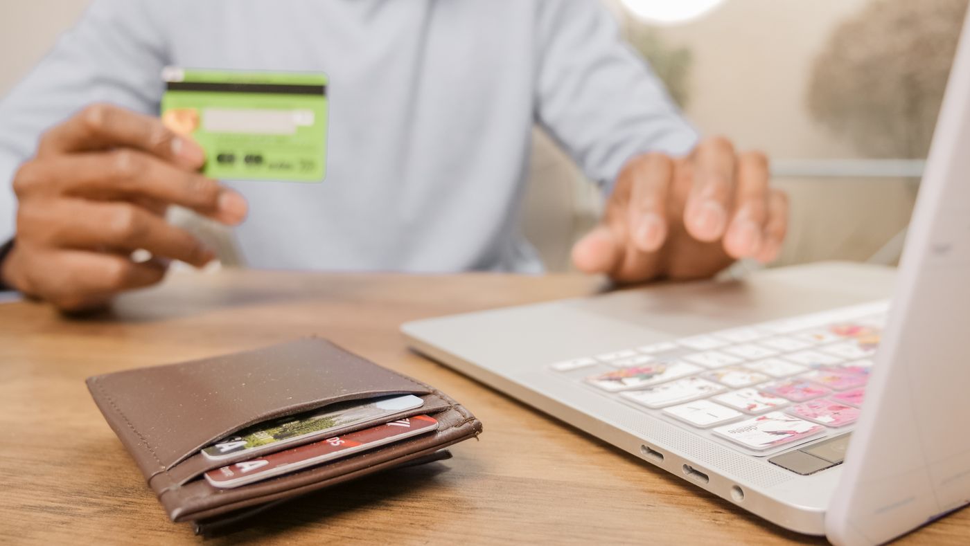 Person using a laptop and bank card